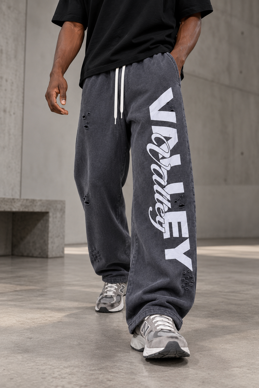 Pantalon jogging large délavé gris anthracite lettrage Valley porté par un homme, vue de trois quarts